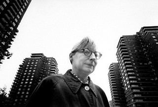 Jane_jacobs_1965_wide_small Jane Jacobs in glasses with apartment towers in the background.
