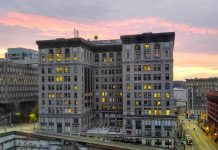 King County Grapples with Public Defender Crisis A ten story building with a pinkish purple sunset in the background