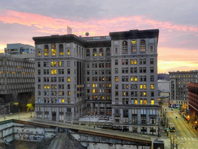 A ten story building with a pinkish purple sunset in the background