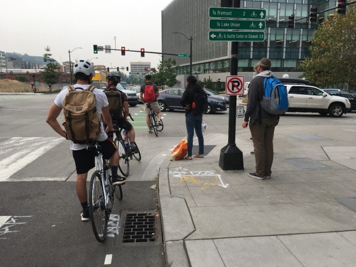 Mercer Street clogged with cars Three people biking and two pedestrians wait for a long line of cars queuing on Mercer Street in South Lake Union.