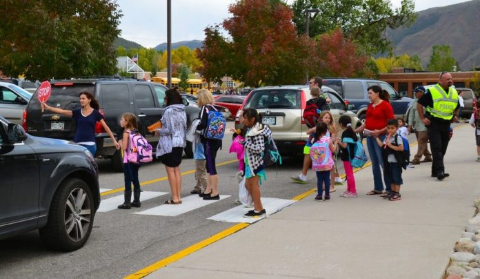 Traffic+Congestion+at+School A school crosswalk busy with students and parents in a sea of cars.