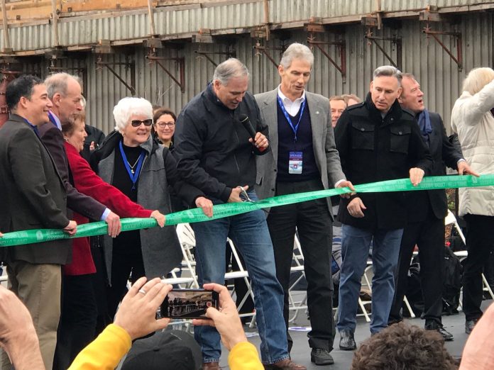 cuttingRibbonSR99tunnel Inslee holds the scissors and other high-level officials look on outside the SR-99 tunnel in February 2019.