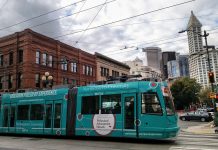 Center City Streetcar Dominates at Initial Transportation Budget Discussion teal streetcar in Pioneer Square with Smith Tower and other buildings