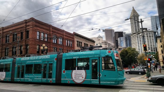 Center City Connector teal streetcar in Pioneer Square with Smith Tower and other buildings