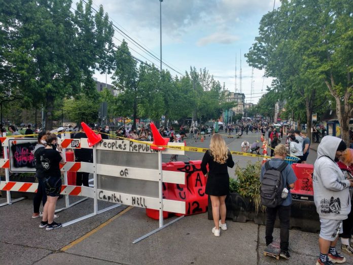 People look on a cordoned off Pine Street just before protesters add "Black Lives Matter Way" in big block letters. (Photo by author)