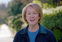 Durkan Text Scandal Whistleblowers Sue City for Retaliation Mayor Durkan stands on a sidewalk on a leafy residential block.