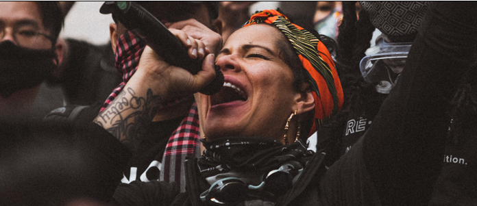 2021-03-29 Nikkita Oliver projecting into a microphone.