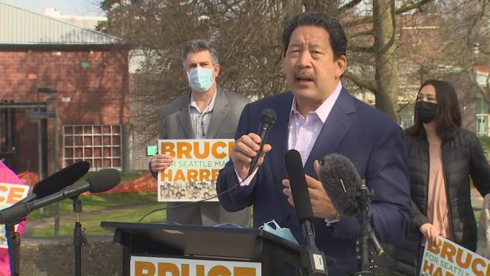 Bruce Harrell in a suitcoast with a microphone in hand at his candidacy announcement press conference.