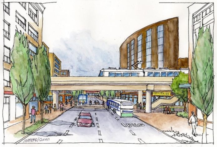 An elevated light rail line over a city street with midrise buildings on the sides.