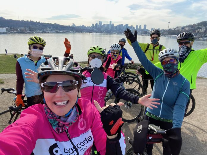 Cascade Bike Club cyclists near Gasworks Park Seattle A group of cyclists wearing colorful athletic clothes poses near their bicycles in front of Lake Union in Seattle.