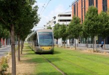 Envisioning a Car-Free Aurora Avenue A modern tram runs along grass in Nice with midrise building and trees flanking.
