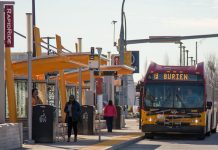 The Urbanist Podcast: Is Transit Back? A photo of people wait for an arriving King County Metro Bus at a RapidRide station.