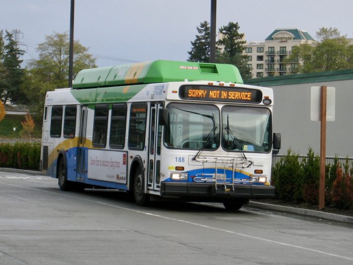0C1AE2A5-CBF5-49BF-971B-2D4F4B13EF48_1_201_a A white, blue, and green bus runs with a not in service sign.