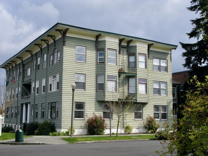 5B77D6BE-1299-4CD0-96DD-A678A1ABCBF7_1_201_a A photo of a light green gray three story apartment building.