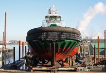 Foss Lost: Shipyard Closure as a Barometer for Resiliency A photo of a black, green, and red tugboat on a platform over the water.