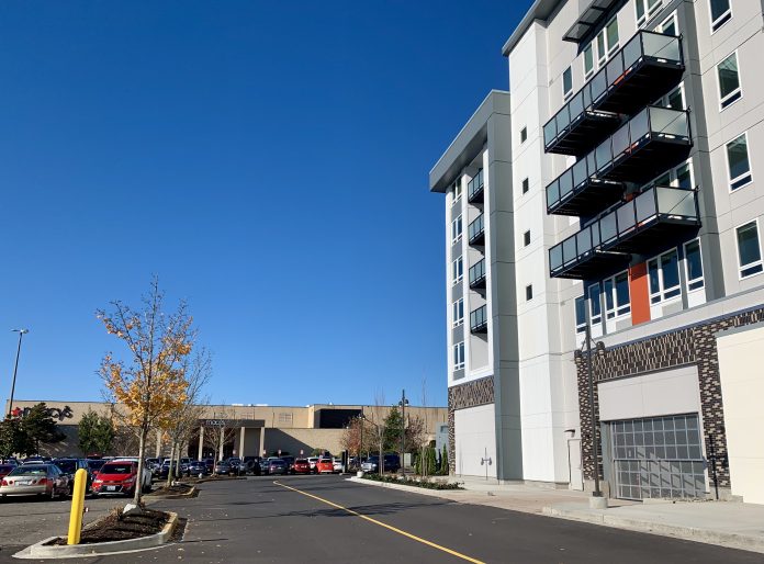 Alderwood Mall Lynnwood A photo of an apartment next to a parking to with cars and an indoor mall.