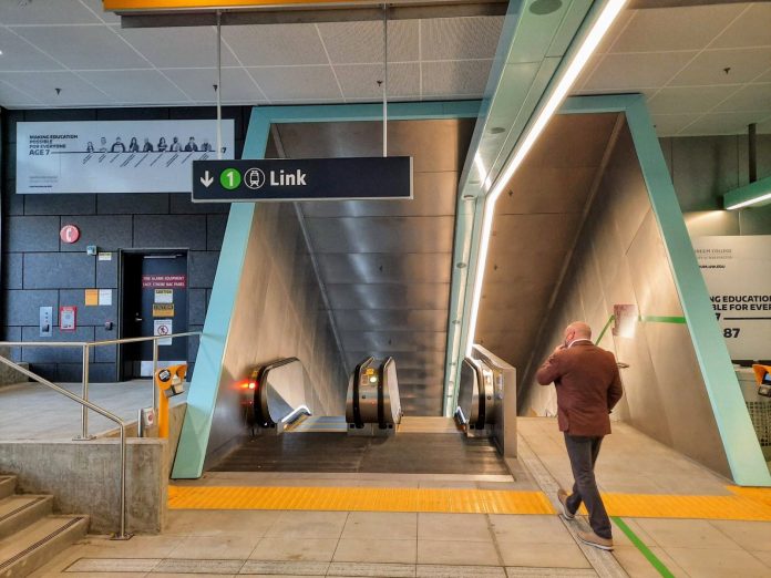 U District Station entrance with escalator 20211001 A man walks toward the escalator down to the station platform.