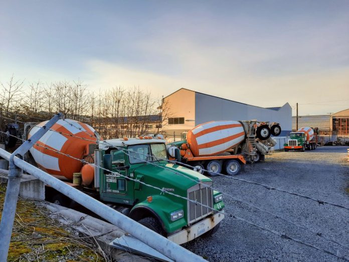 A gravel lot with three concrete mixer trucks.