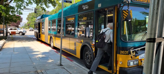 A passenger boards a bus A man board an articulated bus.