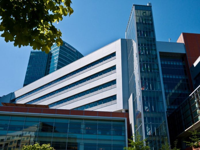 9D9F4A8E-C8BC-46AB-93BB-44784322C245_1_201_a A photo of a large modern building with a leafy tree branch in front of it.