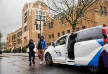 Metro Flex Microtransit Expands to Issaquah White van with passenger door open waits for riders in front of a brick building.