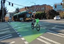 As Development Slows, Seattle Eyes Transportation Impact Fee Projects Someone riding a lime bike across a bike lane in Capitol Hill with a bus behind them