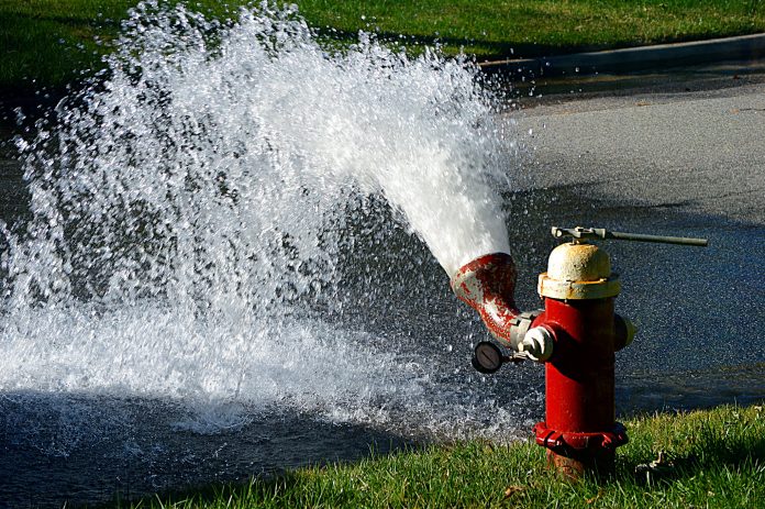 44622813805_80d096f4bc_k A red fire hydrant shows a five foot geyser of water on some green grass.
