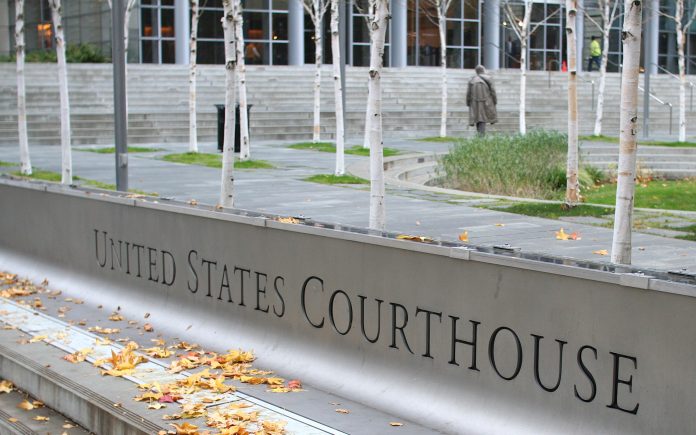 ErinHyundiLawsuitUSCourthouse Eric E. Johnson photo Sign for United States Courthouse, stairs and person walking to the entrance through skinny trees