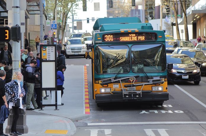 King_County_Metro_2619_on_6th_Avenue_in_Downtown_Seattle Route 301 using the 6th Avenue bus lanes in Downtown Seattle with a dozen riders waiting at a busy combined bus stop.
