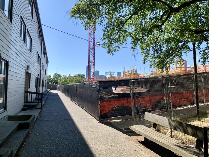 Bryant Manor construction site Existing housing separated by a sidewalk from a large construction site with crane.