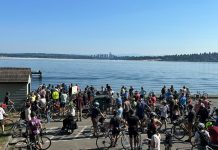 The Results Are In on The Urbanist’s First Annual Reader Survey A group of about 50 bicyclists stand on the shores of Lake Washington with Bellevue in the background.