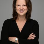 Portrait photo of Amy Walen, smiling, with arms crossed in front of her, black sweater and shoulder length dark hair.