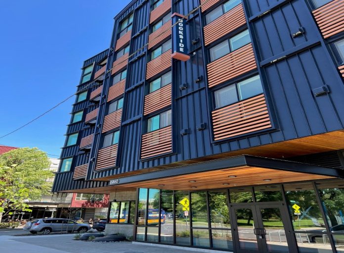 A six-story apartment building with blue metal siding and wood railing for juliette balconies