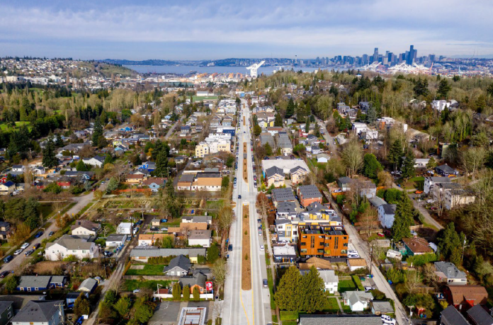 Delridge An aerial photo of a boulevard with port cranes and Elliott Bay in the distance.
