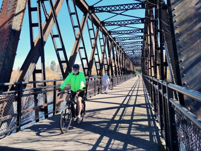 .Trestle bike/ped bridge A person bikes on a trestle bridge with a few pedestrians in the background.