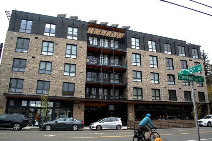 Shared-Roof-exterior-2-andrew-engelson-1280 A bike whizzes by on Greenwood Avenue with a brick building in the background