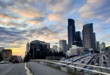 Why Climate Advocates Should Be Urbanists, Part 1 I-5 and the Seattle Skyline at sunset looking down Yesler Way to Elliott Bay with Smith Tower peeking out on the left and the car-clogged I-5 trench on the right.