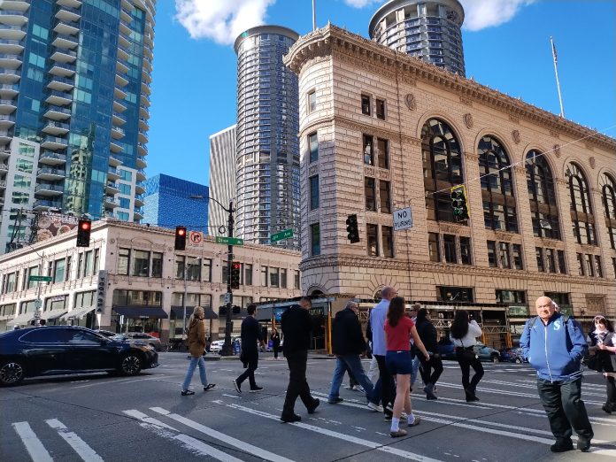 A crosswalk is filled with a dozen pedestrians in downtown Seattle.