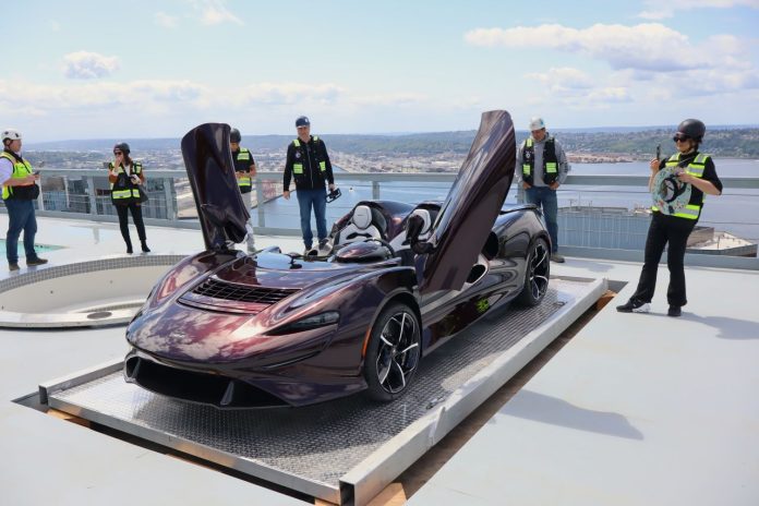 McLaren Wings Spread with Onlookers - Trumm IMG_0583 McLaren has its butterfly doors up while a half dozen onlookers in yellow vests take picture or admire the car.