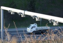 Washington Cities Question Use of License Plate Readers Citing Federal Overreach A photo shows a row of plate reader cameras over a highway with a truck going by.