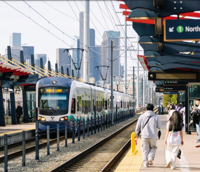 Rainier Valley light rail station by Sound Transit Two riders walked down the platform with the Seattle skyline in the distance.