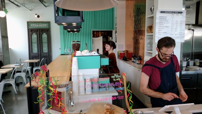 Servers at Cafe in Wallingford 20170216 Two servers behind the counter at a cafe, one at the register and another at the espresso machine.