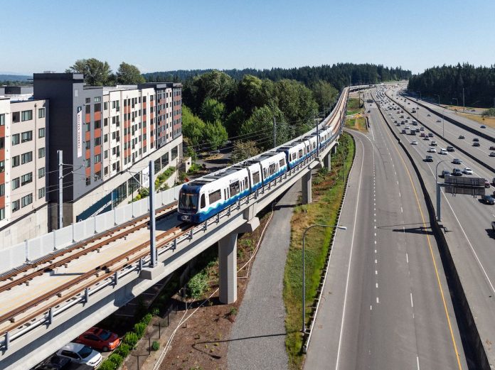 Lynnwood_Link_Testing-PB-3 at Mountlake Terrace Peter Bohler Elevated light rail tracks skirt Interstate 5 and a midrise residential building in Mountlake Terrace.