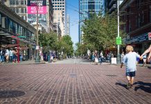 Urbanism 101: 15-Minute Cities, Walkability, and Accessibility A parent with a toddle in hand on a brick plaza.