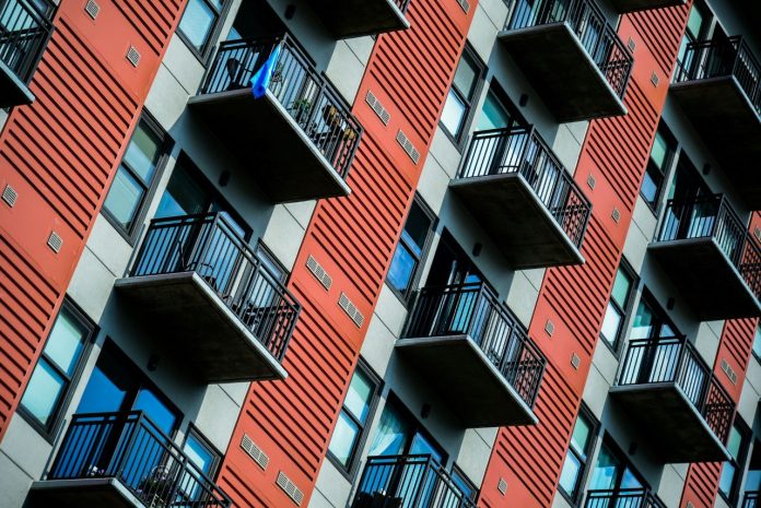khay-edwards-uMwq36_p0ts-unsplash 1280 A tall red residential building with balconies.