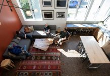 The Case for Converting Vacant Offices to Congregate Housing Four residents sit in a L couch in a lounge well-lit by natural light.