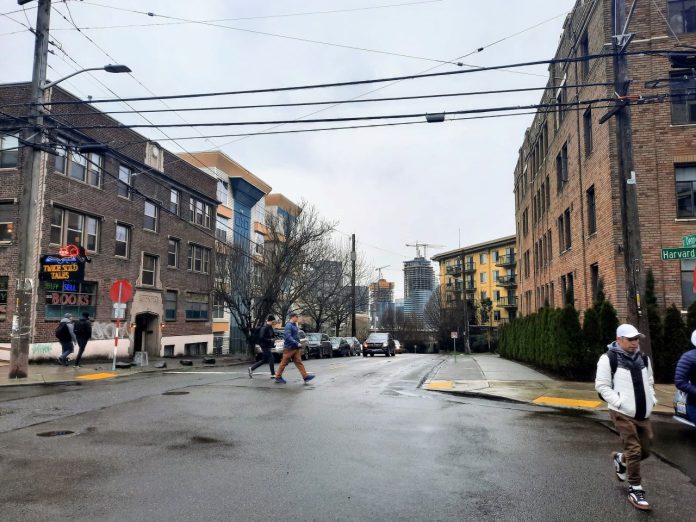 Harvard Avenue in Capitol Hill Seattle - Trumm 20230204 Pedestrians cross Denny Way at the Harvard Avenue intersection with midrise apartment buildings in the background.