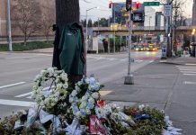 Metro Plans Reduced Service as Staff Hold Shawn Yim Memorial Friday The pedestrian bridge to the University Washington campus looms in the background and a bus stop with two buses waiting at a stop light.