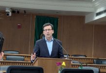 Ferguson Proposes ‘Unprecedented Sweep’ of Climate Dollars to Balance State Budget Ferguson stands at the lectern wearing a navy suit and glasses in a Capitol board room.