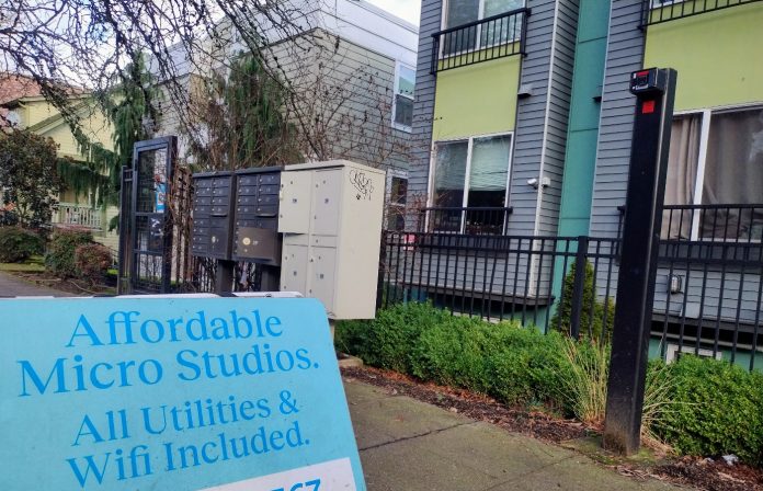 Rental sign A sign in front of an apartment building advertising "Affordable Micro Studios" with utilities and wifi included